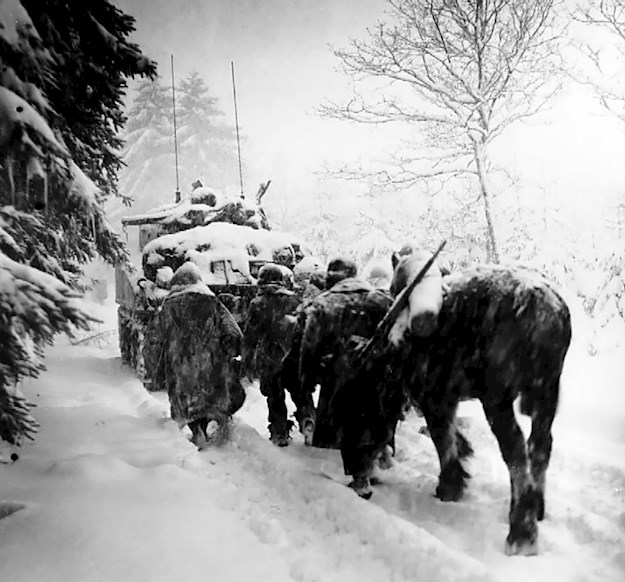 Troops of the 82nd Airborne Division advance in a snowstorm behind the tank in a move to attack Herresbach, Belgium. 28 January 1945.