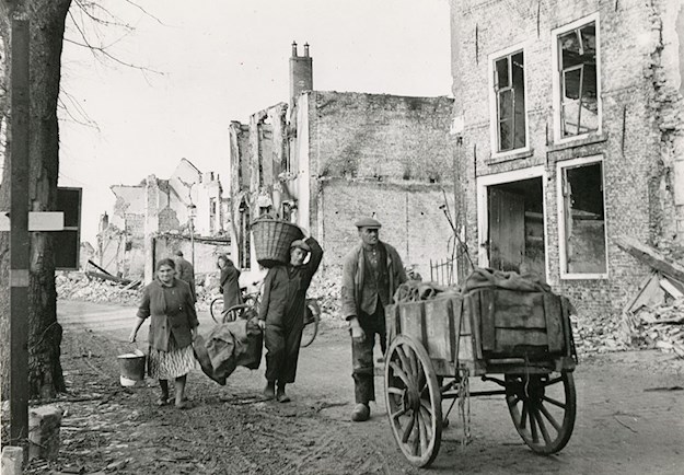 Dutch civilians walk through the ruined town of Breskens, destroyed during the Battle of the Scheldt.