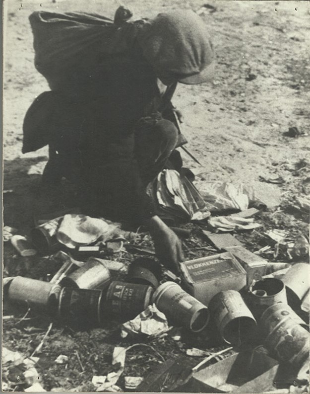 Young boy looking through garbage to find something edible during the ‘Hunger Winter’.