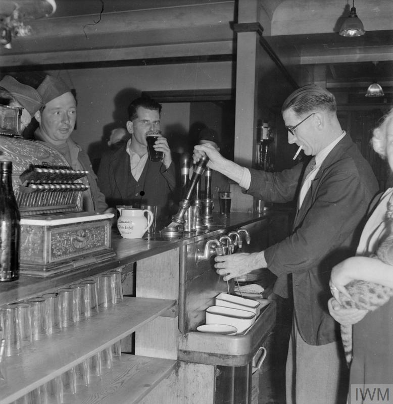 A PICTURE OF A SOUTHERN TOWN: LIFE IN WARTIME READING, BERKSHIRE, ENGLAND, UK, 1945 (D 25361) A barman pulls a pint for an American soldier at a typical pub, somewhere in Reading.  The photograph is taken from behind the bar, and the ornate till or cash register can be clearly seen. Copyright: © IWM. Original Source: http://www.iwm.org.uk/collections/item/object/205202142